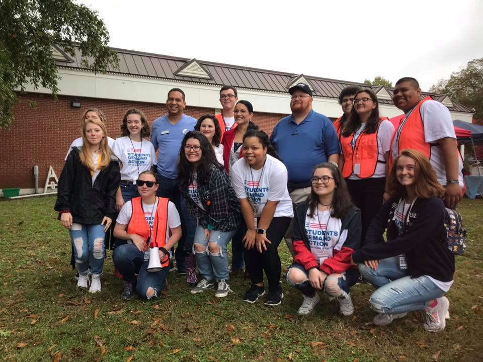 Image from an election day rally, a crowd of students and adults standing together smiling for a picture.